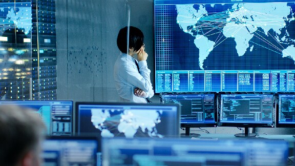 Man looking at a world map displayed on a screen in a System Control Room