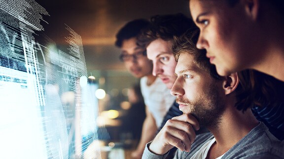 Four people next to each other looking at a virtual computer display