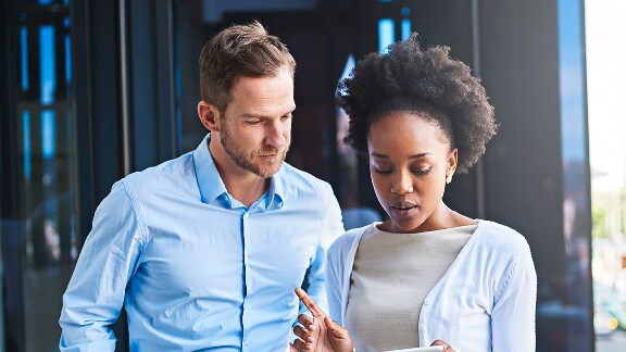 Two people standing in an office looking at a tablet