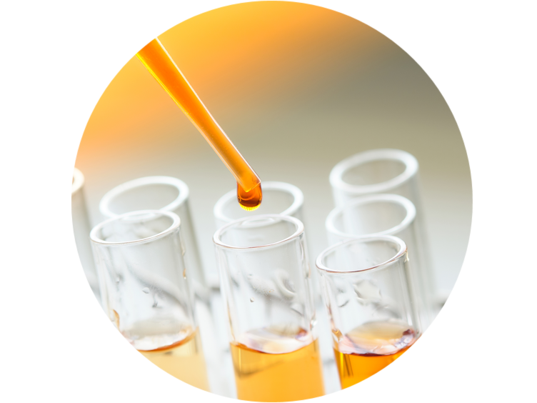 A dropper dropping an orange liquid in test-tubes