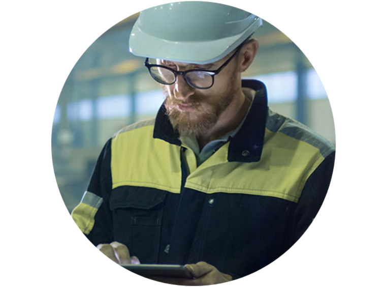 A man wearing glasses and safety equipment looking down at a tablet