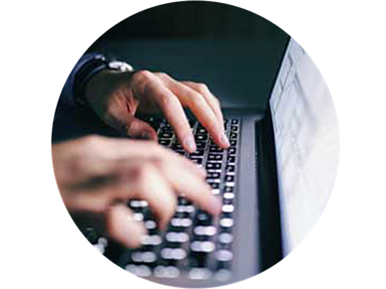 Close-up of a person's hands typing on a laptop keyboard